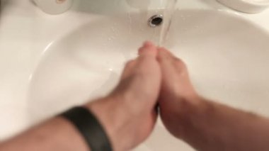 Adam beyaz bir lavaboda ellerini yıkar.