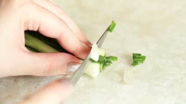 Жіночі руки розрізали зелену цибулю на дрібні шматочки . — стокове відео