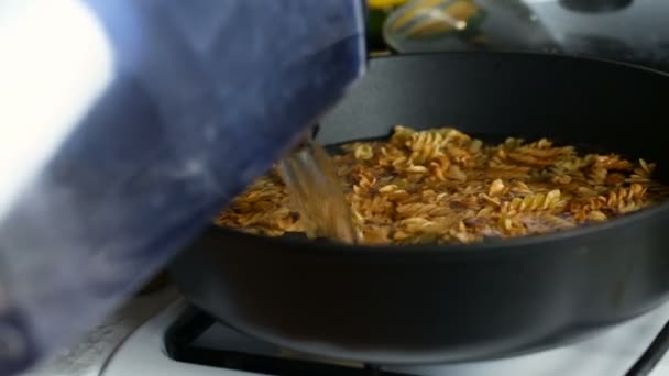 Вода добавляется в сковородку с жареными макаронами . — стоковое видео
