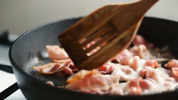 Pala de madera revuelve jamón frito en una sartén . — Vídeo de stock