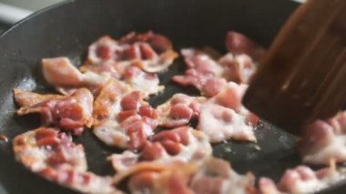 Ahşap kürek bir tavada kızarmış jambon kıpırdanırken.