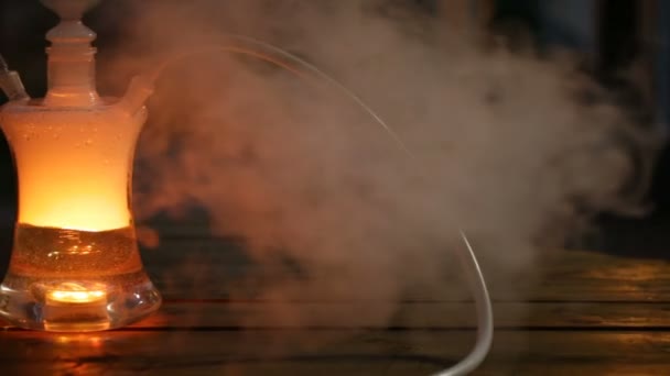 Fotoaparát se pohybuje na rovnou na levé a odstraní skleněná vodní dýmka s osvětlení na stůl v noci. — Stock video