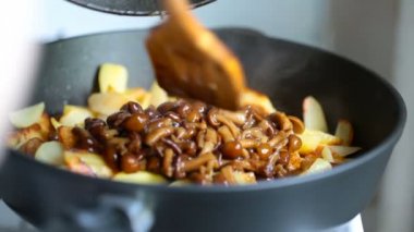Patates kızartması ve karışık tahta spatula ile tavada kızartılmış mantar eklenir.