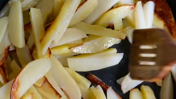 Wooden shovel stirs crisp potato in a frying pan. — Stock Video