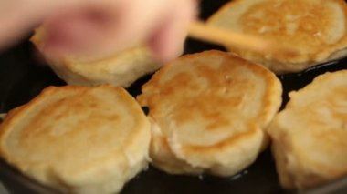 Erkek flip krep tahta spatula ile bir tavada kızarmış eller.