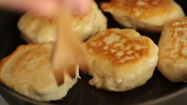 Frauenhände blättern Pfannkuchen in einer Pfanne mit Holzspachtel gebraten. — Stockvideo