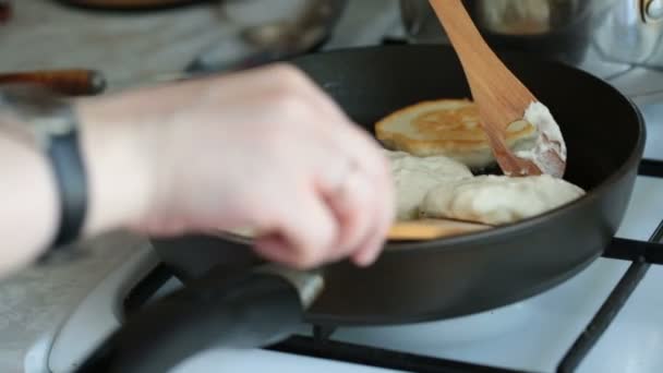 Női kezek flip palacsinta egy serpenyőben fa spatula. — Stock videók