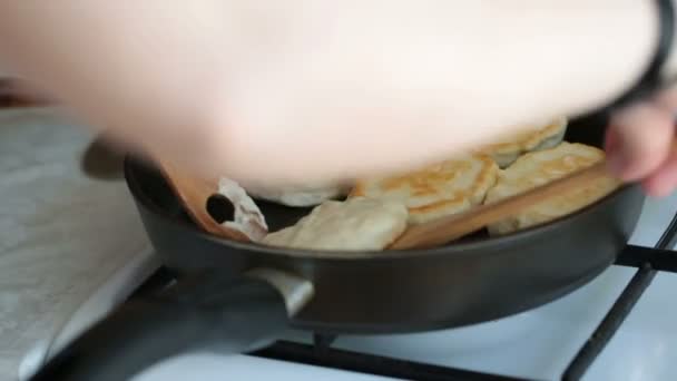 Руки женщины переворачивают блины в сковородке с деревянной лопаткой. . — стоковое видео