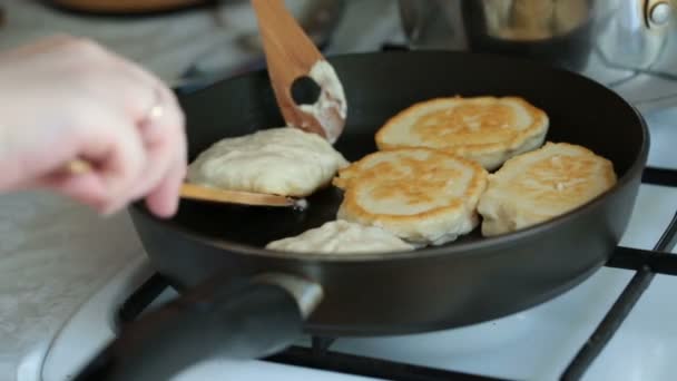 Θηλυκό τα χέρια κτυπήματος τηγανίτες σε ένα τηγάνι με ξύλινη σπάτουλα. — Αρχείο Βίντεο