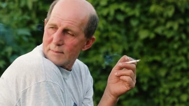 Мужчина среднего возраста курит в парке — стоковое видео