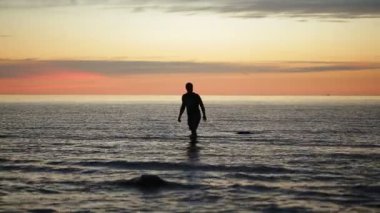 İnsan akşam deniz kenarında yürüyor.