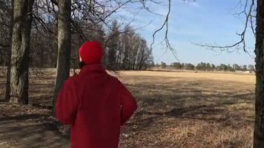 Kamera onu takip atlet kırmızı giysili park sokak üzerinde çalışır.