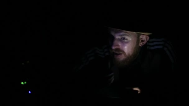 Бородатый мужчина освещает смартфон в темноте — стоковое видео