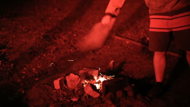Man blaast de kolen in het bos bij nacht — Stockvideo
