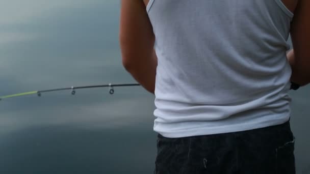 Молодой рыбак настраивает удочку — стоковое видео