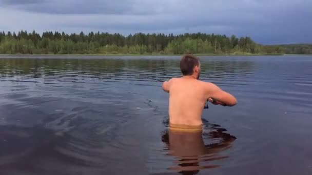 Молодой человек рыбачит в воде по пояс — стоковое видео