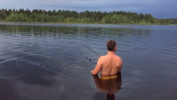 Joven está pescando en el agua hasta la cintura — Vídeos de Stock