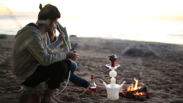 Mann mit dem Mädchen, das am Lagerfeuer in der Natur eine Wasserpfeife raucht — Stockvideo