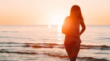 Güzel kız denizde günbatımı zamanında poz