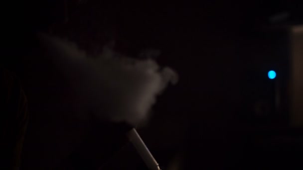 Ο άνθρωπος καπνίζει ναργιλέ σε ένα σκοτεινό δωμάτιο — Αρχείο Βίντεο