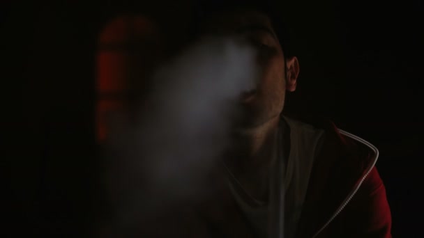 Man smokes hookah in a dark room — Stock Video