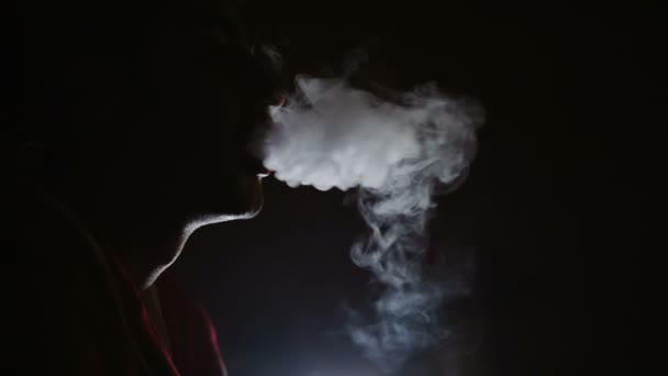 Чоловік курить кальян у темній кімнаті — стокове відео