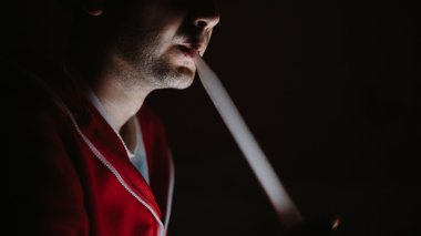 Adam karanlıkta sigara içiyor.