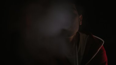 Adam karanlıkta sigara içiyor.