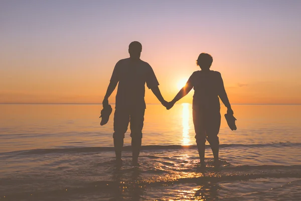 Happy senior couple silhouettes on the beach — Stockfoto