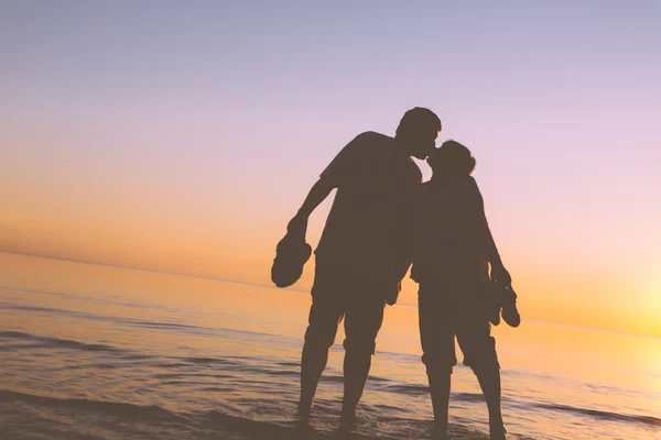 Glückliches älteres Paar Silhouetten am Strand küssen — Stockfoto