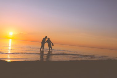 couple de personnes âgées s'embrasser au coucher du soleil