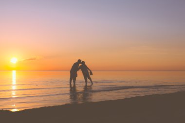 couple de personnes âgées s'embrasser au coucher du soleil