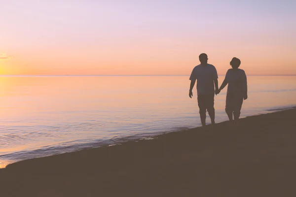 Couple aîné marchant le long de la plage — Photo