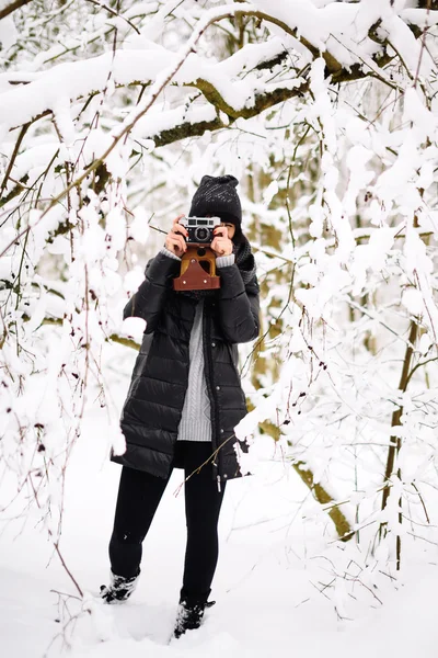 Jente med vintage kamera i vinterskogen – stockfoto