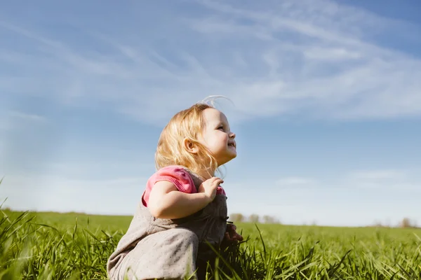 Little girl sitting in grass — Stock Photo, Image
