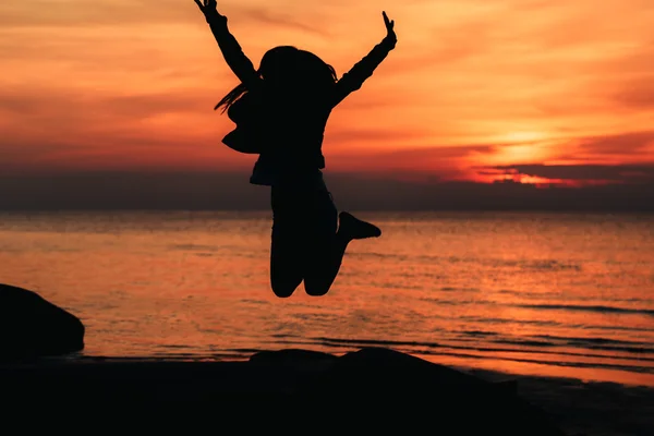 아름 다운 석양을 배경으로 한 실루엣 점프 소녀 — 스톡 사진