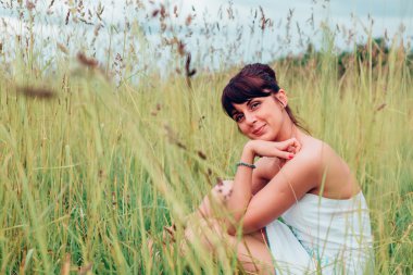 Oturma ve bir çayır üzerinde poz kız.