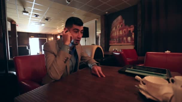 Jonge man zakenman aan de telefoon bij café — Stockvideo