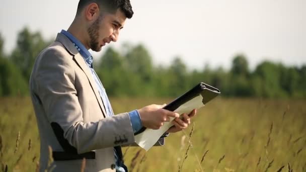 Mladý muž podnikatel hledá výkresy na povaze — Stock video