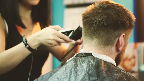 Peluquero corta el cabello del cliente con un cortador . — Vídeo de stock