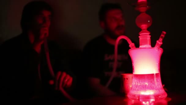 Young men smoking shisha in dark room. — Stock Video