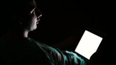 Genç karanlık odada dijital tablet bilgisayar kullanarak adam ve diyor.
