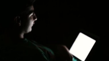 Genç karanlık odada dijital tablet bilgisayar kullanarak adam ve diyor.
