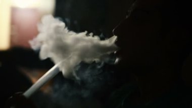Genç adam sigara nargile karanlık bir odada.