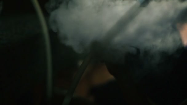 Main tient un tuyau de narguilé contre une fumée .