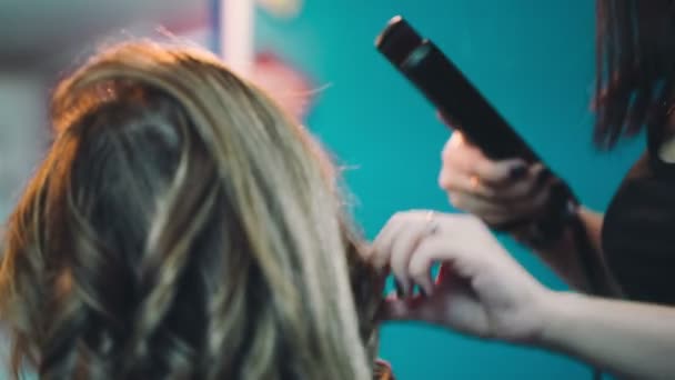 Peluquería alisa el cabello del cliente . — Vídeos de Stock