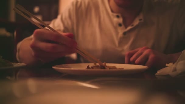 Young man eats with Japanese sticks. — Stock Video