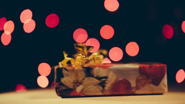 Weihnachtsgeschenk dreht sich auf Bokeh-Hintergrund um die eigene Achse. — Stockvideo