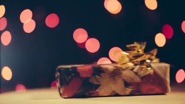 Weihnachtsgeschenk dreht sich auf Bokeh-Hintergrund um die eigene Achse. — Stockvideo