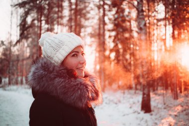 Beyaz bir şapka ve bir arka plan bir kış ormanın bir ceket genç kadın.